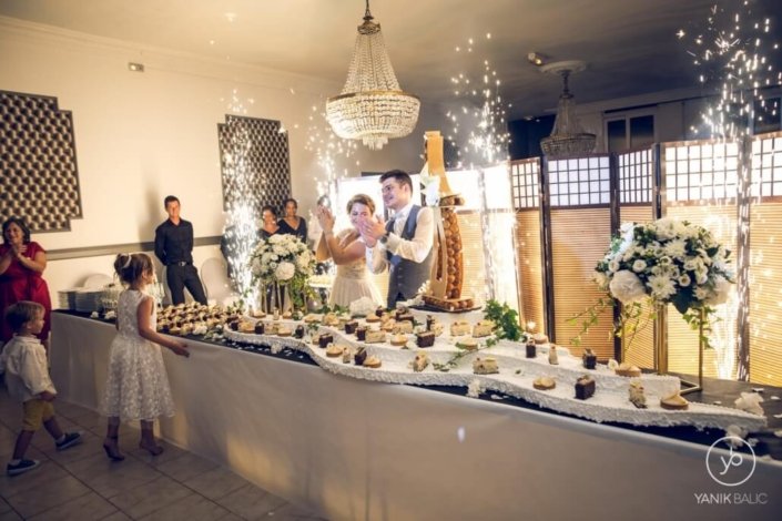 Buffet des desserts du mariage, avec une pièce montée et les mariés derrière