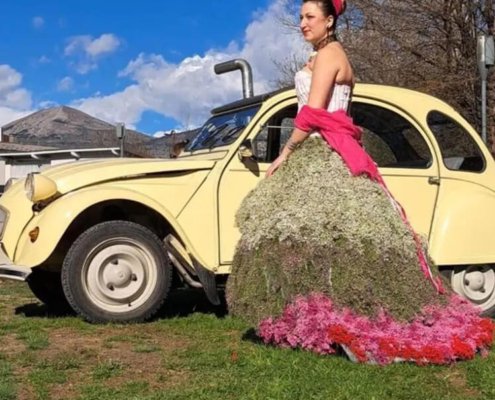 Photo de Mélodine portant la robe florale dans un champ, à côté d'une voiture vintage