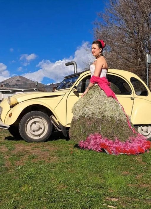 Photo de Mélodine portant la robe florale dans un champ, à côté d'une voiture vintage
