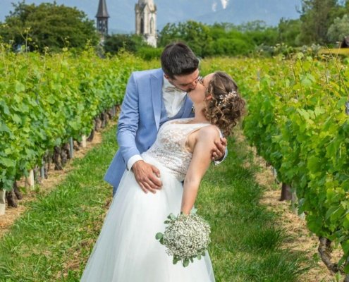 Photo de Chloé et Paul dans un champ, avec en arrière plan l'église et des montagnes enneigées