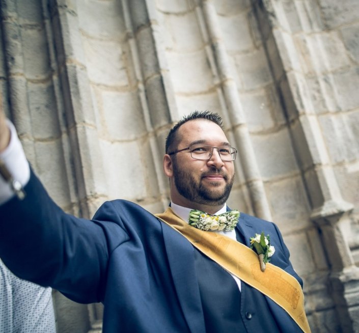 Témoin de mariage en costume portant un nœud papillon en fleurs composé par Mélodine